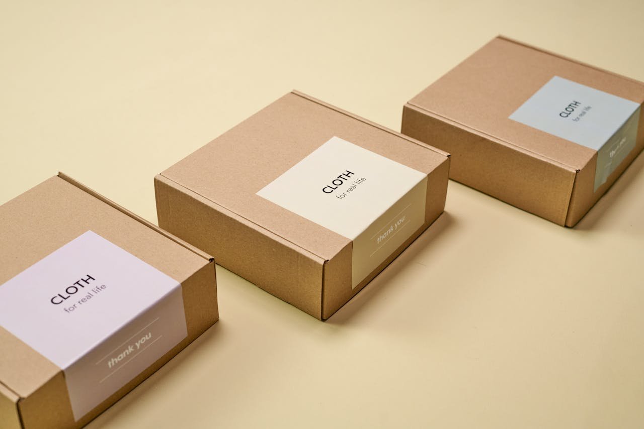 Three minimalist cardboard packages labeled CLOTH on a yellow background.